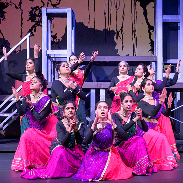 Performers on stage in a posture of prayer or pleading