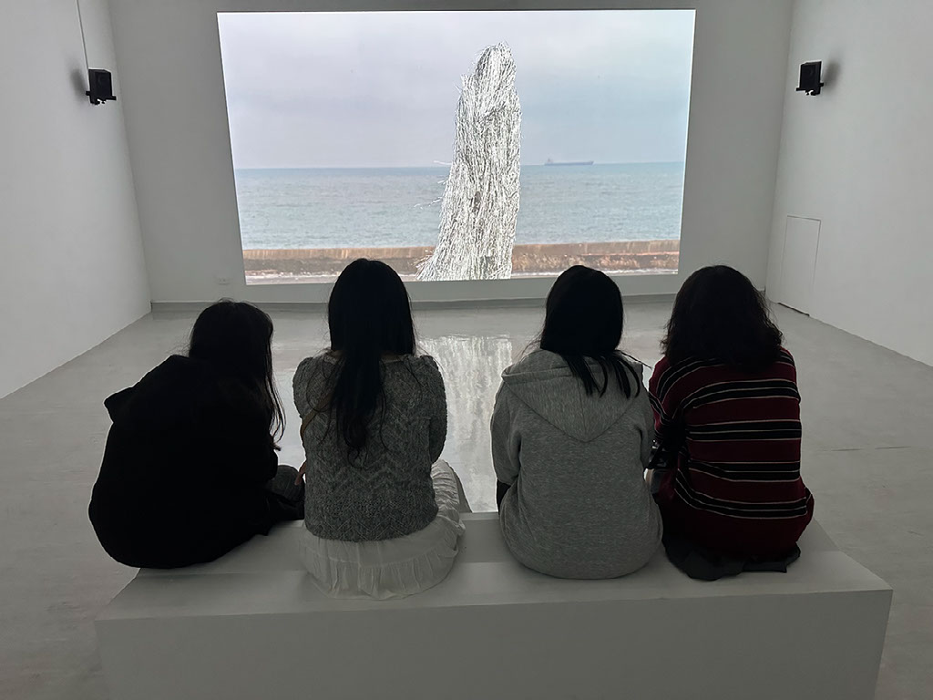 People in an art museum looking at a projection
